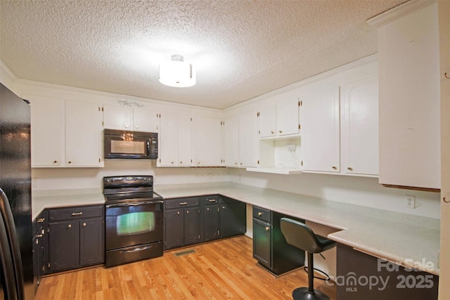 kitchen with light hardwood / wood-style flooring, white cabinets, and black appliances