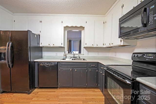 kitchen with a textured ceiling, sink, black appliances, light hardwood / wood-style flooring, and white cabinetry