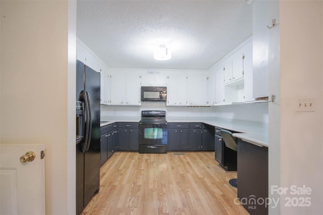 kitchen featuring white cabinets, a textured ceiling, light hardwood / wood-style floors, and black appliances