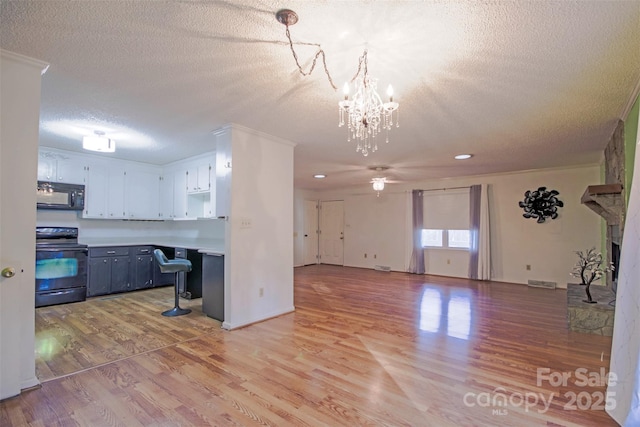 kitchen featuring gray cabinetry, black appliances, light hardwood / wood-style flooring, white cabinets, and hanging light fixtures