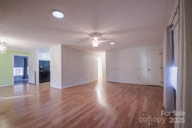 unfurnished room with a textured ceiling, ceiling fan, crown molding, and light hardwood / wood-style flooring