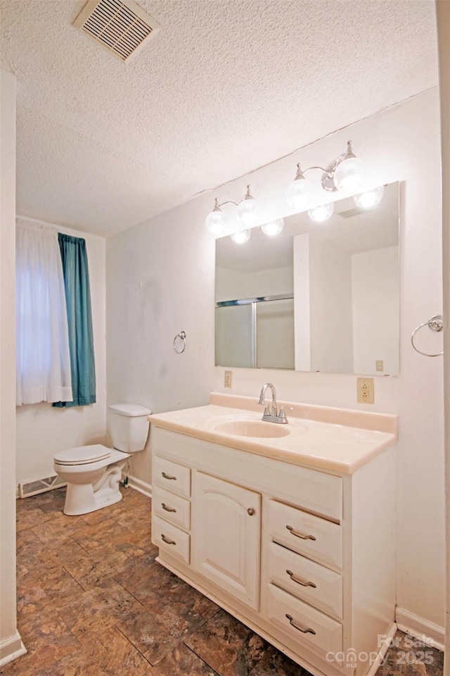 bathroom featuring vanity, a shower with shower door, a textured ceiling, and toilet