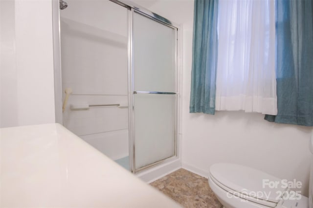 bathroom with toilet and a shower with door