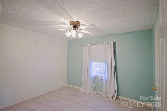 empty room with ceiling fan, light hardwood / wood-style floors, and a textured ceiling