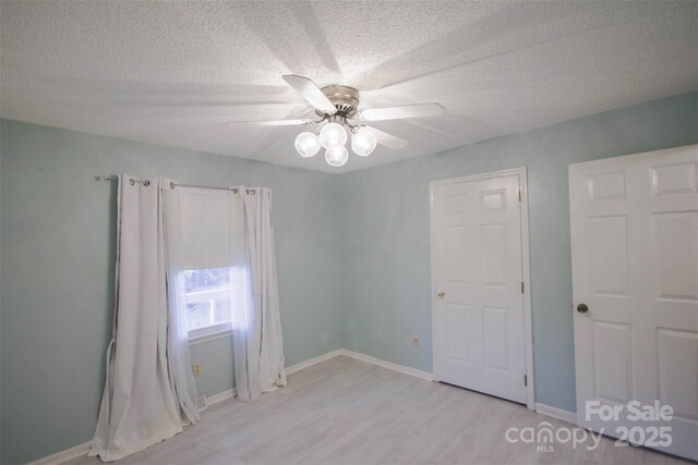 spare room featuring ceiling fan, light hardwood / wood-style flooring, and a textured ceiling