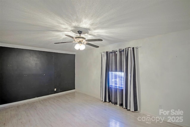 spare room with ceiling fan, light hardwood / wood-style floors, and a textured ceiling