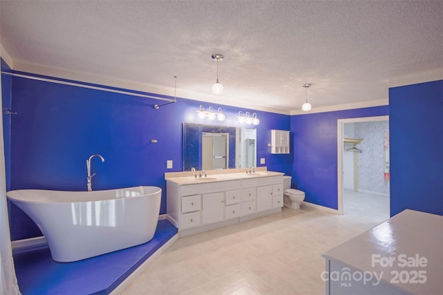 bathroom with a bathing tub, vanity, toilet, and a textured ceiling