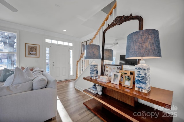 living room featuring light hardwood / wood-style floors, ceiling fan, and ornamental molding