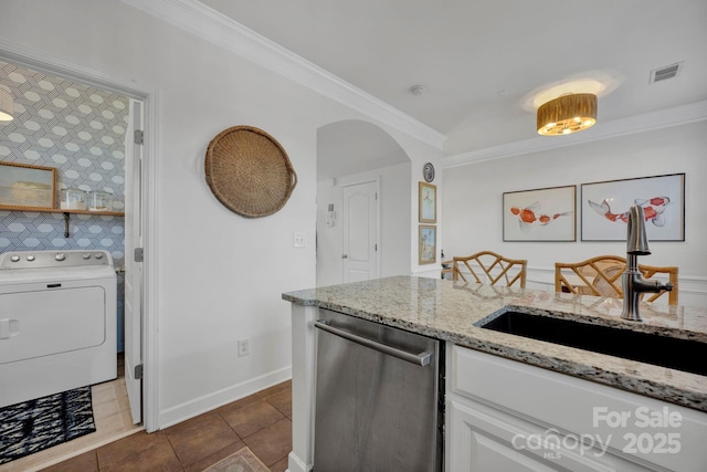 kitchen featuring dishwasher, sink, light stone countertops, washer / dryer, and white cabinetry