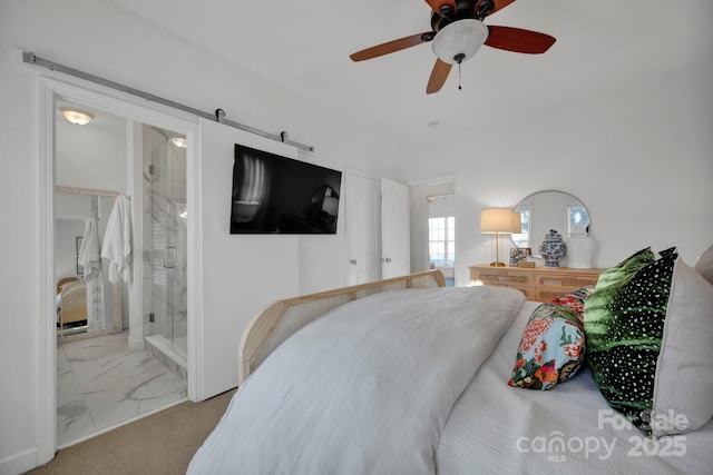 bedroom featuring connected bathroom, ceiling fan, and a barn door