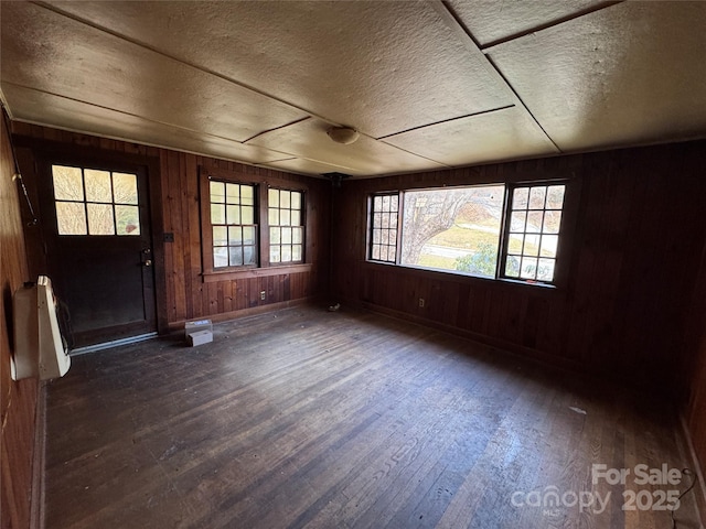 foyer entrance featuring a textured ceiling, dark hardwood / wood-style flooring, and wood walls