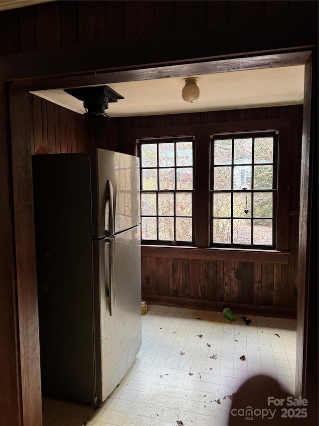 kitchen with stainless steel fridge and wood walls