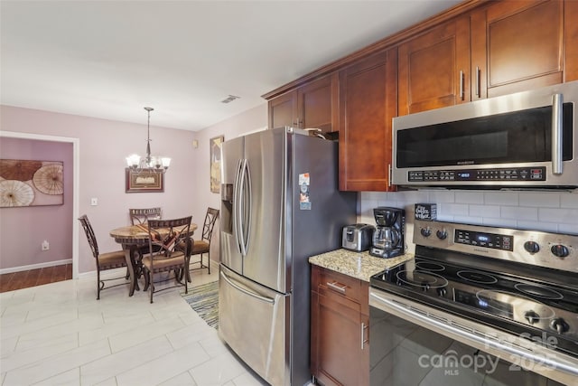 kitchen with hanging light fixtures, light stone counters, backsplash, a chandelier, and appliances with stainless steel finishes