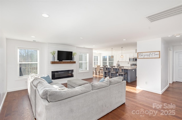 living room featuring a wealth of natural light, a large fireplace, and hardwood / wood-style floors