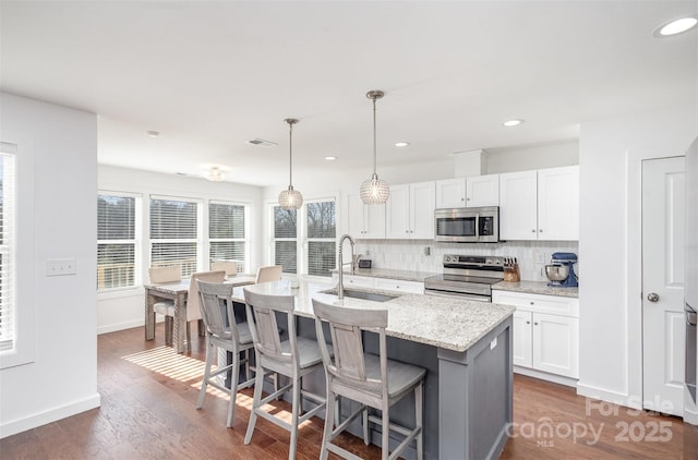 kitchen with a center island with sink, stainless steel appliances, white cabinetry, and sink