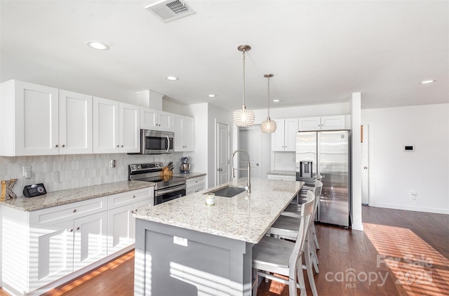 kitchen with stainless steel appliances, an island with sink, white cabinets, and sink