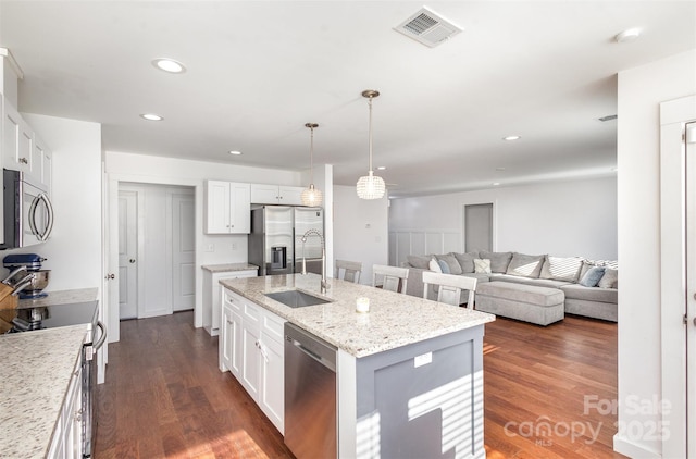 kitchen featuring white cabinetry, appliances with stainless steel finishes, a center island with sink, and sink