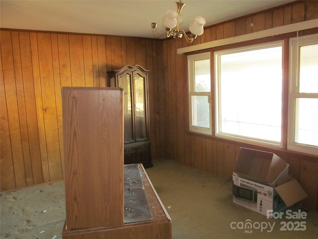 misc room featuring wood walls and an inviting chandelier