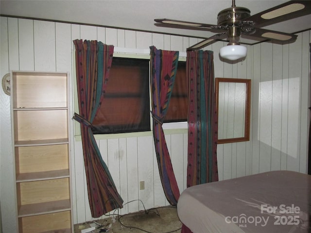 bedroom with ceiling fan and wooden walls