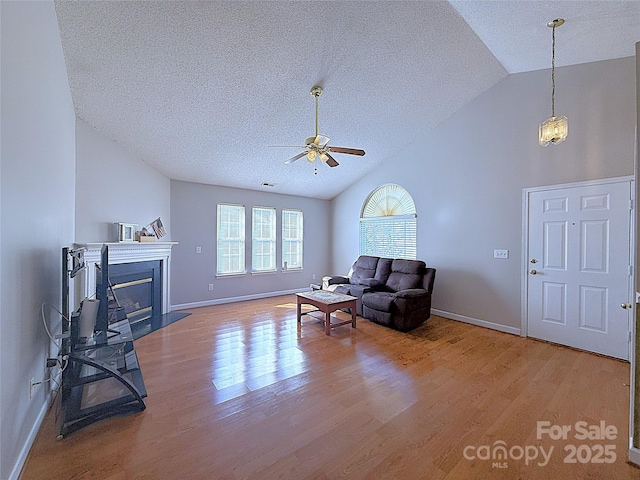 living room featuring ceiling fan with notable chandelier, wood-type flooring, lofted ceiling, and a textured ceiling