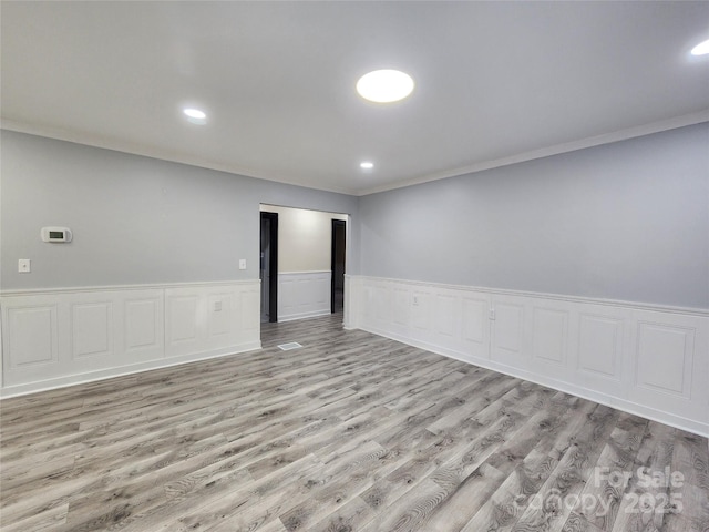 spare room featuring ornamental molding and light wood-type flooring