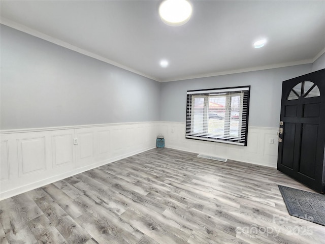 entrance foyer featuring crown molding and light wood-type flooring