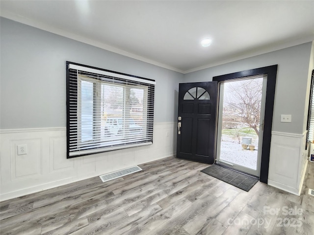 foyer entrance with light hardwood / wood-style floors and crown molding