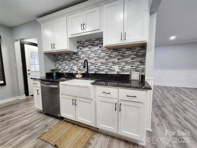 kitchen featuring white cabinetry, light hardwood / wood-style floors, decorative backsplash, dark stone counters, and stainless steel dishwasher