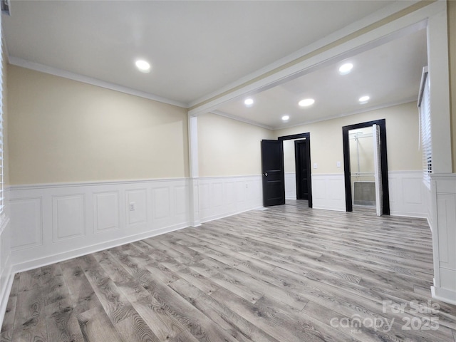 empty room with ornamental molding and light hardwood / wood-style floors