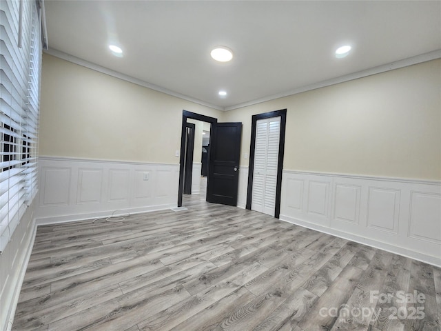 unfurnished room with light wood-type flooring and crown molding