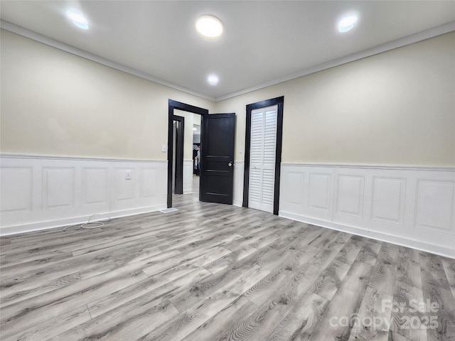 empty room with crown molding and light wood-type flooring