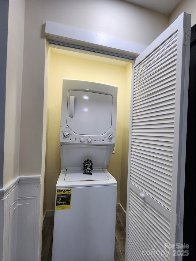 laundry room featuring dark hardwood / wood-style flooring and stacked washer and dryer