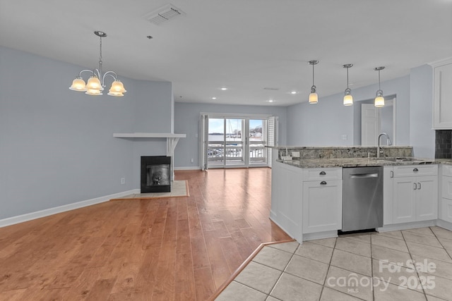 kitchen featuring white cabinets, stainless steel dishwasher, a sink, light wood-type flooring, and open floor plan