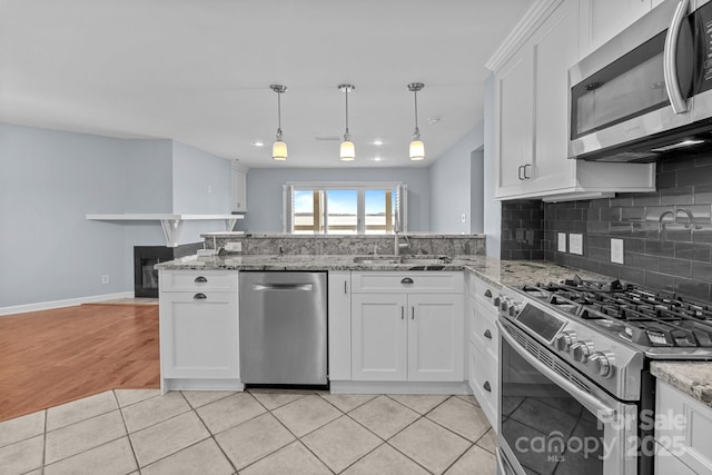 kitchen with stainless steel appliances, a peninsula, a sink, tasteful backsplash, and white cabinetry