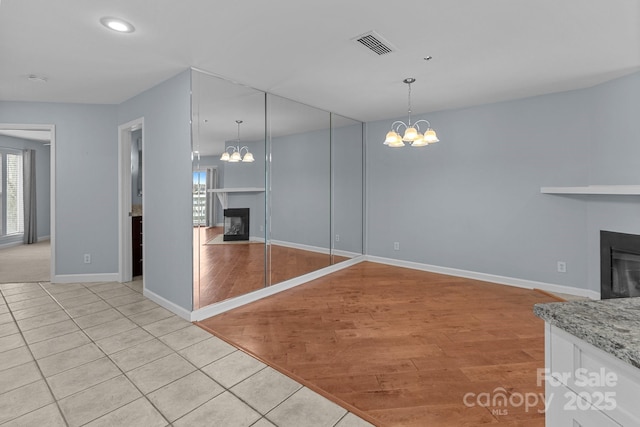unfurnished living room featuring visible vents, a fireplace, and a notable chandelier