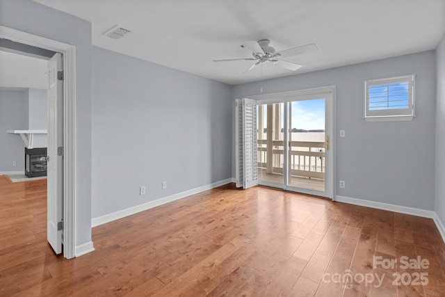 unfurnished room featuring baseboards, a ceiling fan, wood finished floors, and visible vents