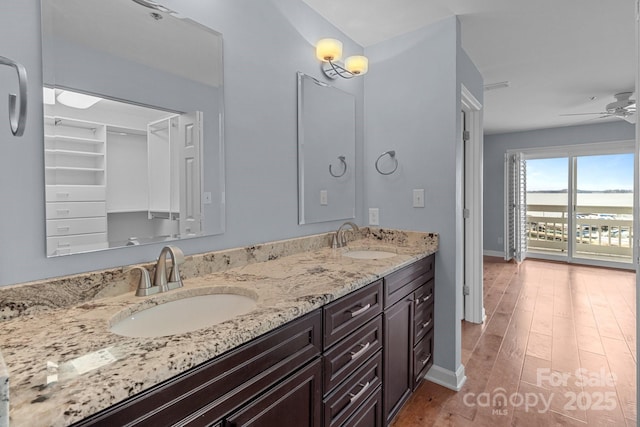 full bath featuring double vanity, wood finished floors, ceiling fan, and a sink