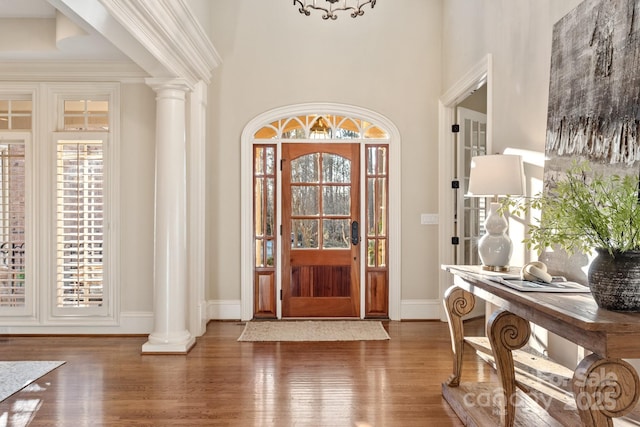 entrance foyer featuring decorative columns, dark hardwood / wood-style floors, and a healthy amount of sunlight