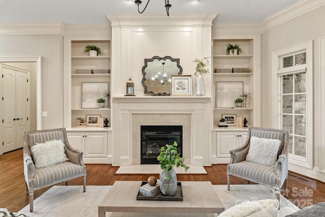 sitting room with built in shelves, light hardwood / wood-style flooring, and crown molding