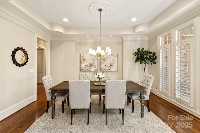 dining area with hardwood / wood-style floors, a raised ceiling, and a notable chandelier