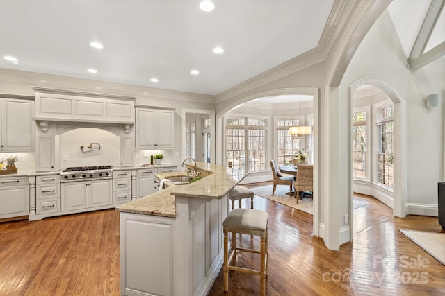 kitchen featuring sink, light hardwood / wood-style flooring, a kitchen island with sink, and tasteful backsplash