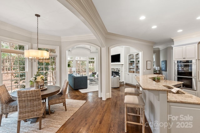 dining room featuring sink, dark hardwood / wood-style floors, and ornamental molding