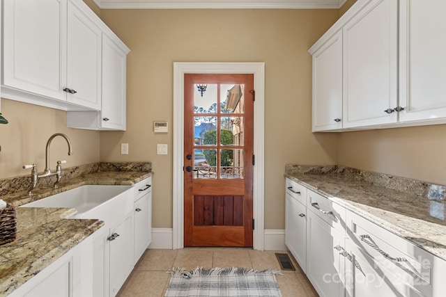 clothes washing area with sink, light tile patterned floors, and crown molding