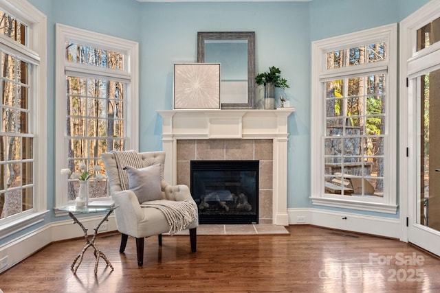 living area featuring a tiled fireplace and hardwood / wood-style floors