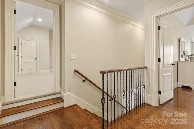 corridor with crown molding, hardwood / wood-style flooring, and vaulted ceiling