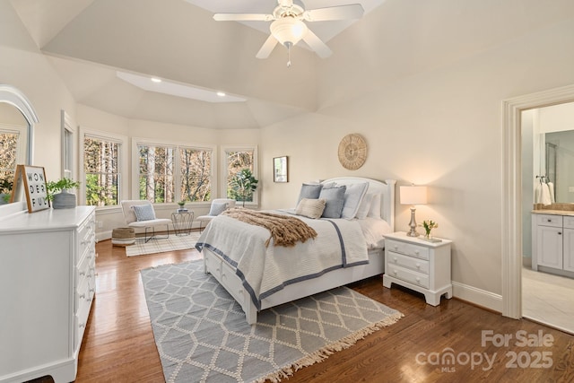 bedroom with ceiling fan, dark wood-type flooring, ensuite bathroom, and vaulted ceiling