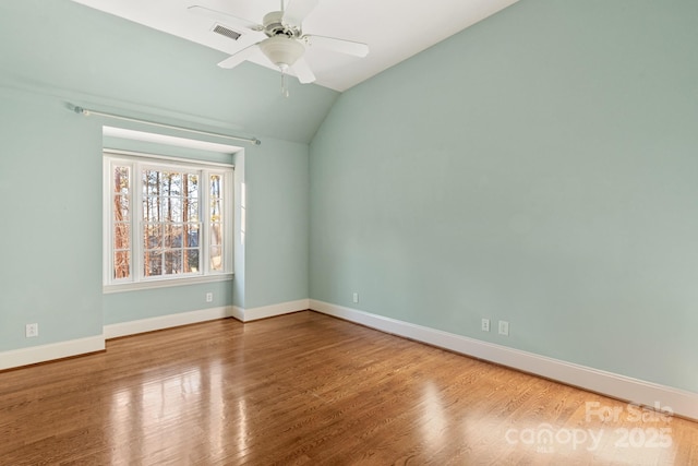 empty room with hardwood / wood-style flooring, ceiling fan, and vaulted ceiling