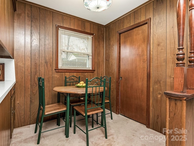 carpeted dining space with wooden walls