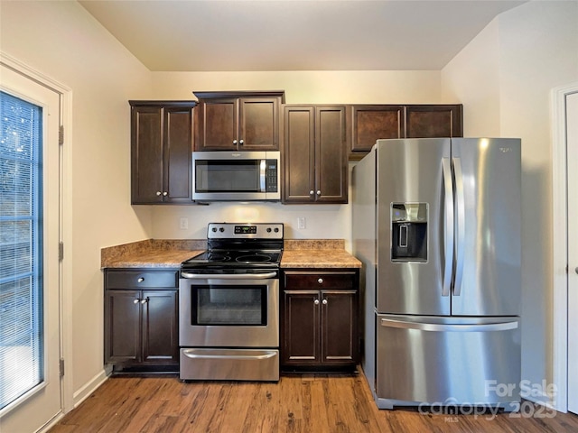 kitchen with dark brown cabinets, stainless steel appliances, and wood-type flooring