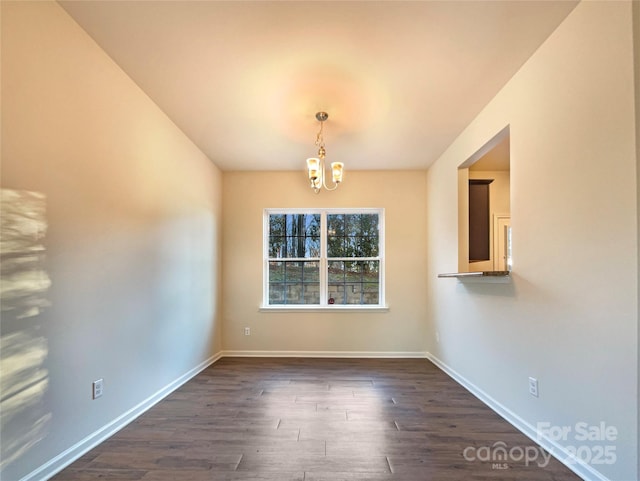 spare room featuring dark hardwood / wood-style floors and a notable chandelier